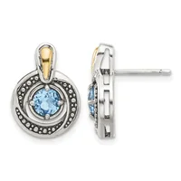 Pair of two-tone stud earrings featuring round light blue gemstones surrounded by beaded silver frames with gold-tone accents, shown from front and side views.