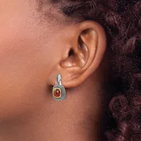 A person wearing a decorative drop earring with a red oval stone surrounded by textured metalwork, shown from the side view against their ear.