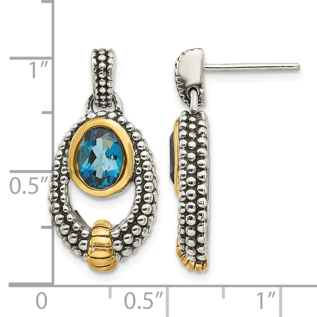 Pair of two-tone drop earrings featuring oval blue topaz stones set in gold bezels, surrounded by beaded silver frames and gold accents, shown against a measurement scale.
