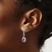 A person wearing a dangling earring with a silver-toned twisted rope design and a purple oval stone set in a gold-toned bezel, shown from the side view of their ear.