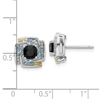 Pair of square stud earrings with black onyx centers surrounded by light blue stones and gold accents, shown against a measurement scale.
