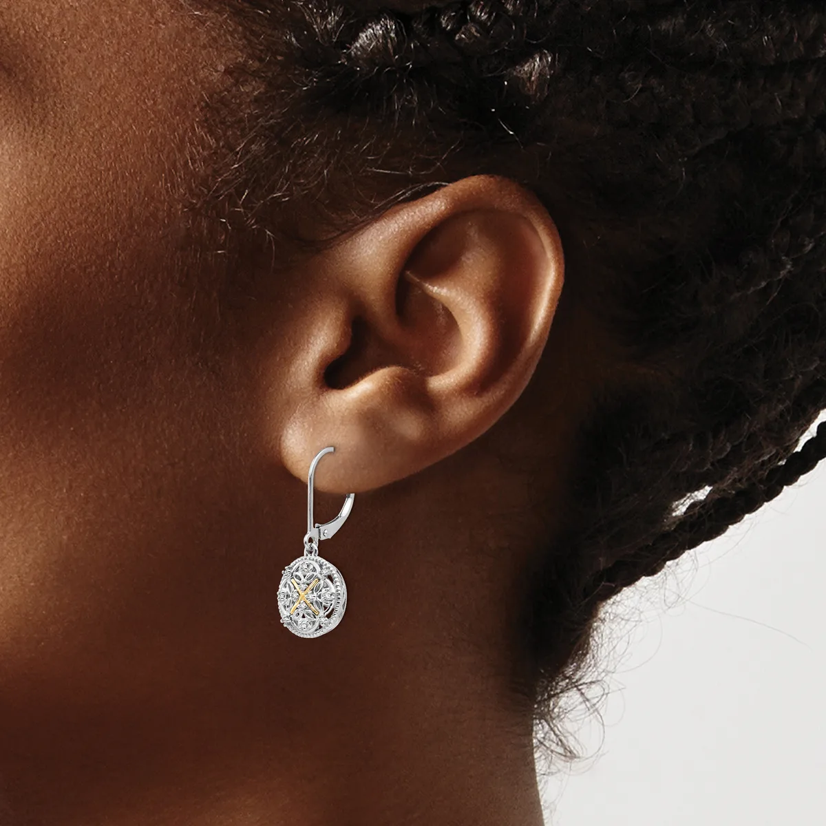 A person wearing a silver lever-back earring with an oval-shaped diamond pendant hanging from the earlobe.