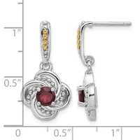 Pair of silver drop earrings with yellow sapphire accents on the posts and a four-lobed flower design pendant featuring a round red gemstone, displayed against a measurement scale.