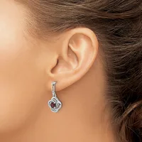 A person wearing a silver dangle earring with a twisted loop design and red gemstone accent, shown on their earlobe in profile view.