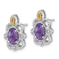 A pair of silver stud earrings with ornate floral designs, each featuring a central oval purple gemstone surrounded by decorative metalwork and a smaller golden yellow stone at the top.