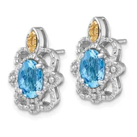 Pair of silver earrings with oval blue topaz stones surrounded by decorative silver filigree and small gold accents at the top, shown from front view.