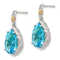 Pair of silver drop earrings with teardrop-shaped blue topaz stones surrounded by textured metalwork and small yellow gemstone accents on the posts.