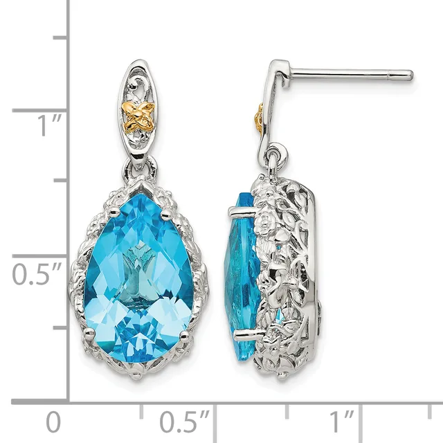 Pair of silver-tone drop earrings with gold accent details, featuring large faceted blue teardrop stones surrounded by ornate filigree settings, shown against a measurement scale.