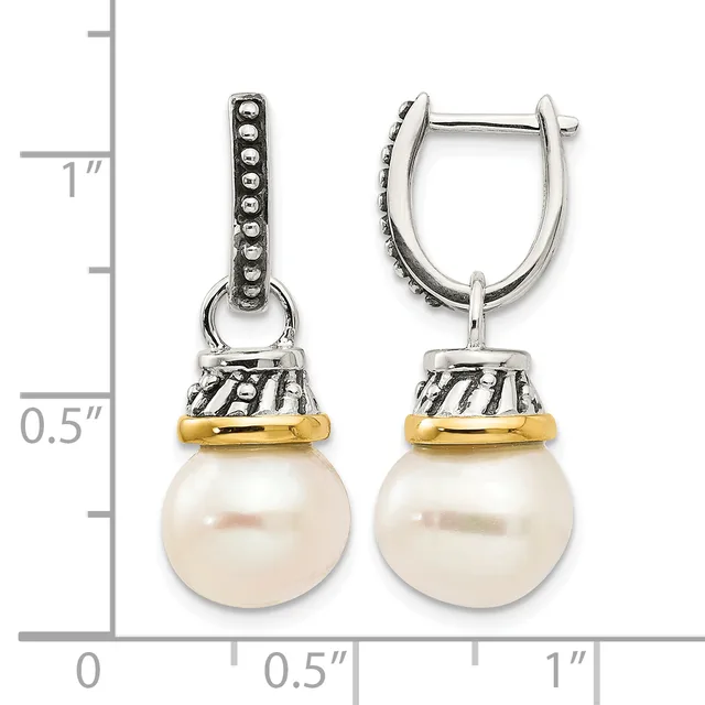 A pair of silver and gold drop earrings with beaded caps suspending round cream pearls, displayed next to a measurement ruler showing approximately one inch in length.