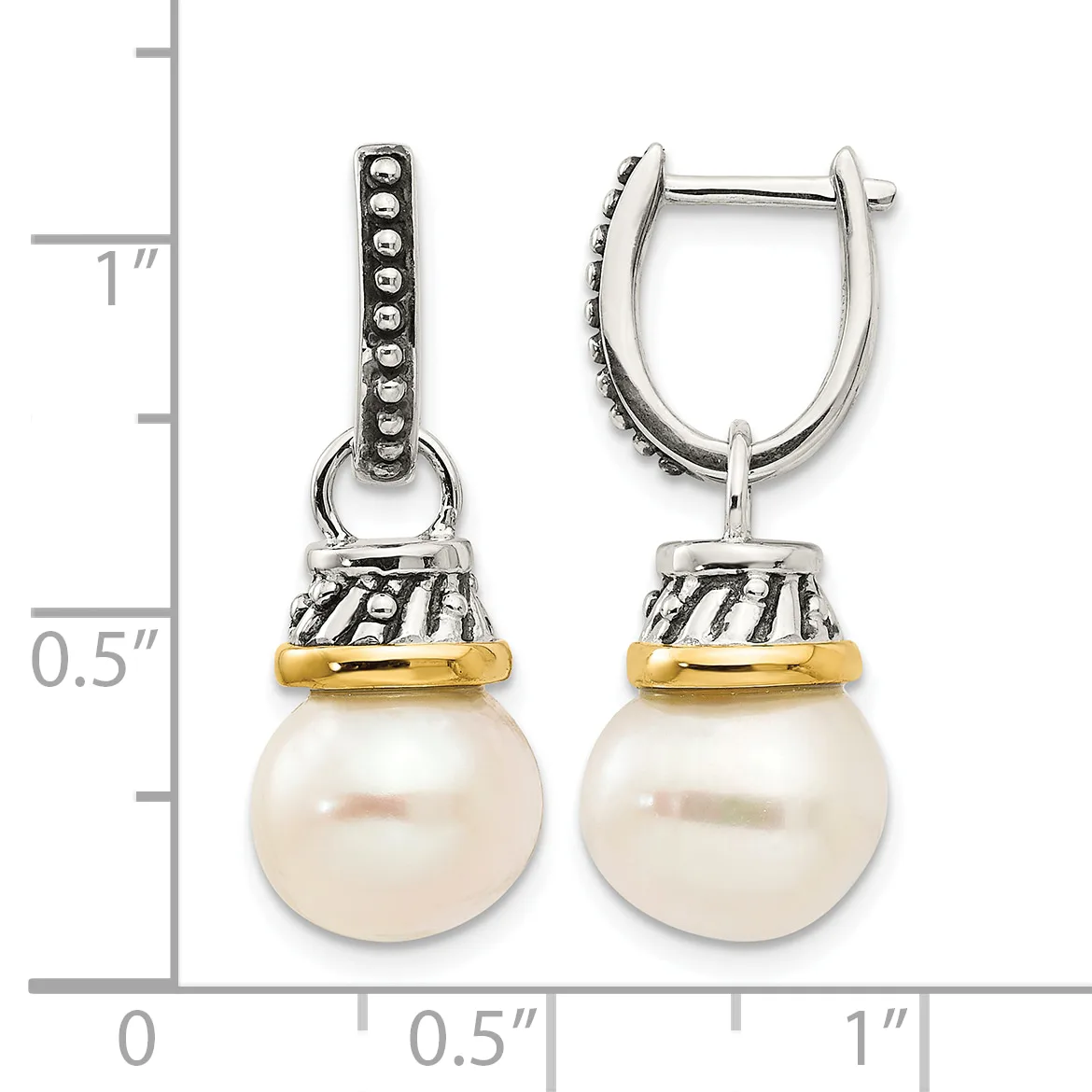 A pair of silver and gold drop earrings with beaded caps suspending round cream pearls, displayed next to a measurement ruler showing approximately one inch in length.