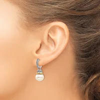 A woman wearing a silver drop earring with a decorative cap and white pearl pendant, shown from the side view near her ear.