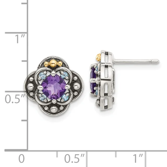 Pair of ornate stud earrings featuring purple faceted gemstones surrounded by light blue stones and decorative metalwork in silver and gold tones, shown against a measurement scale.