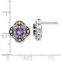 Pair of ornate stud earrings featuring purple faceted gemstones surrounded by light blue stones and decorative metalwork in silver and gold tones, shown against a measurement scale.