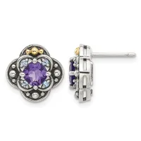 A pair of ornate stud earrings featuring a four-lobed clover design with a faceted purple amethyst center stone surrounded by small round beads and accent stones in silver and gold-tone metal, shown from front and side views.