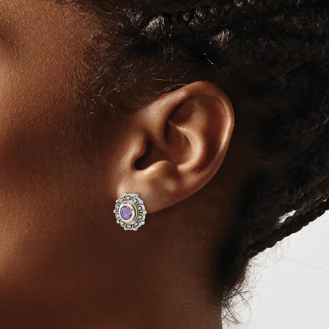 A person wearing a silver oval stud earring with a pale purple gemstone center surrounded by decorative beading, shown from the side view of their ear.