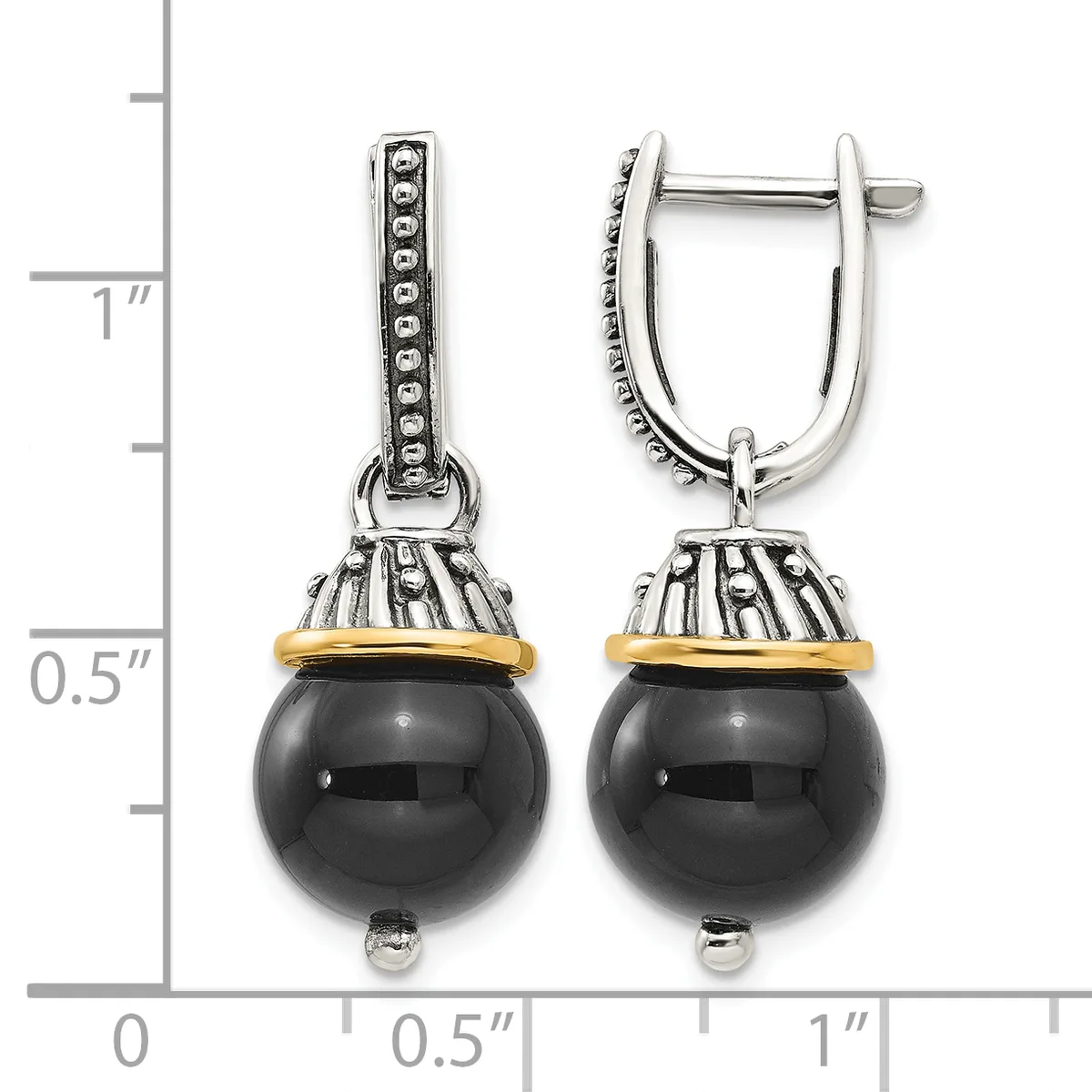 A pair of two-tone drop earrings with polished black onyx spheres suspended from ornate silver caps with gold accents, displayed next to a measurement scale.