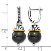 A pair of two-tone drop earrings with polished black onyx spheres suspended from ornate silver caps with gold accents, displayed next to a measurement scale.