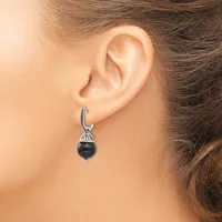 A person wearing a silver hoop earring with a decorative cap and a dangling black spherical stone or bead.