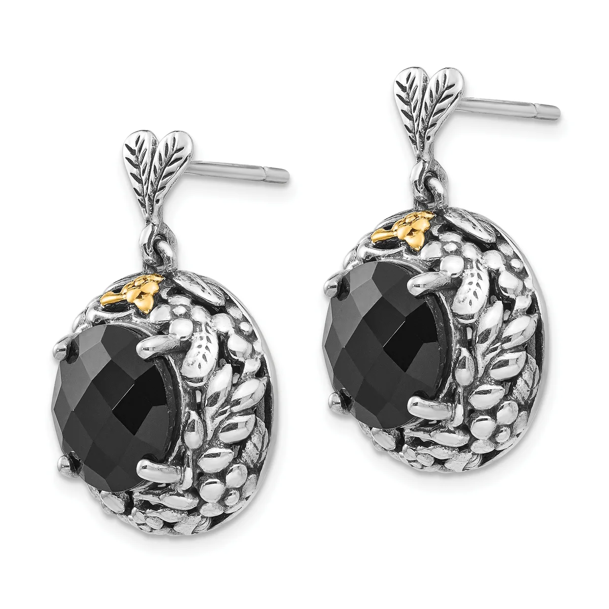 A pair of silver drop earrings with leaf-shaped posts, featuring black faceted oval stones surrounded by textured metalwork with gold-tone accents.