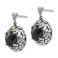 A pair of silver drop earrings with leaf-shaped posts, featuring black faceted oval stones surrounded by textured metalwork with gold-tone accents.
