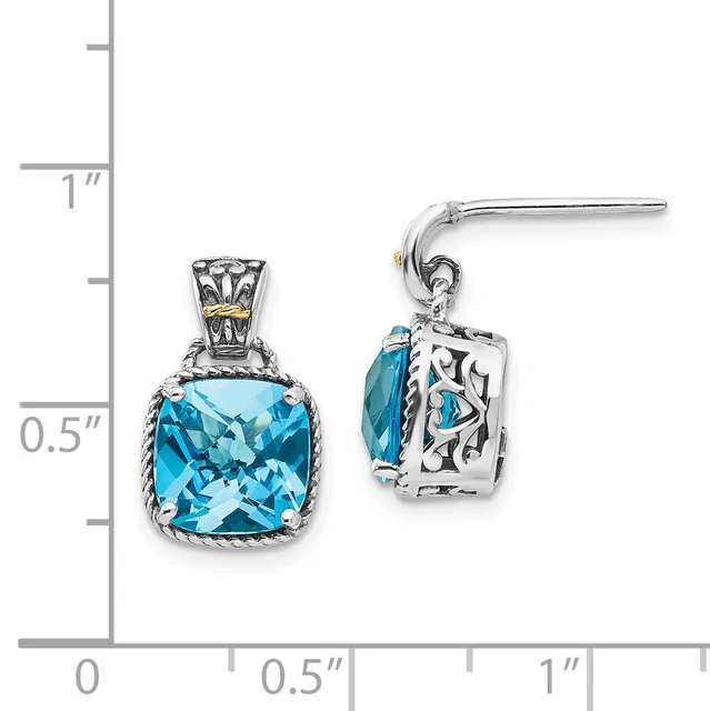 A pair of silver dangle earrings with cushion-cut blue topaz stones set in ornate filigree settings, displayed next to a measurement ruler.