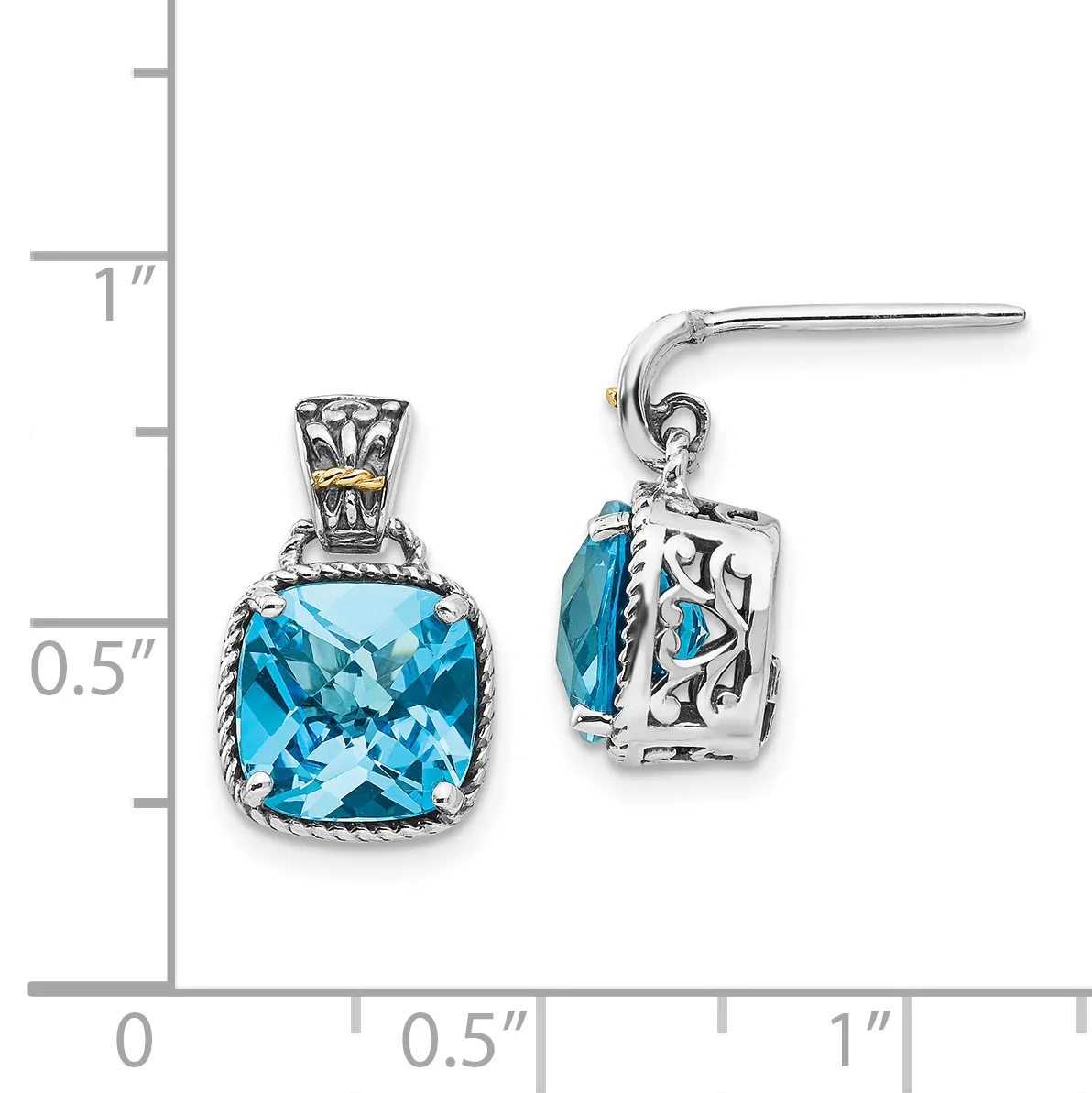 A pair of silver dangle earrings with cushion-cut blue topaz stones set in ornate filigree settings, displayed next to a measurement ruler.