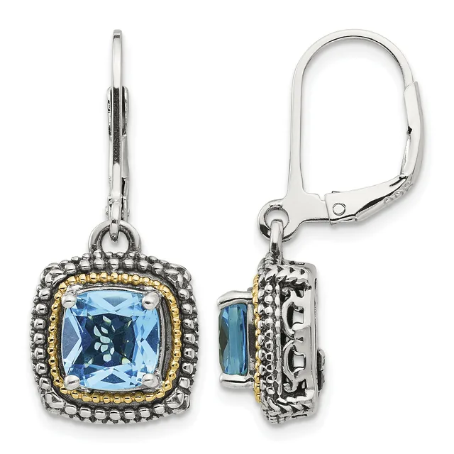 Pair of silver dangle earrings with cushion-cut blue topaz centers surrounded by beaded silver frames with gold-tone accents and leverback closures, shown from front and side views.