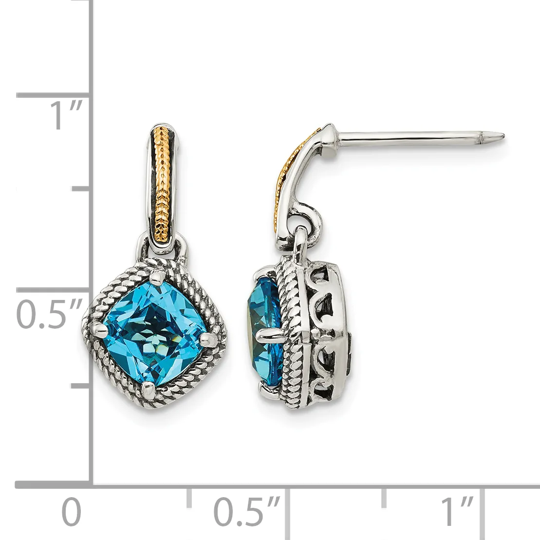 A pair of silver drop earrings with cushion-cut blue topaz stones surrounded by twisted rope detailing and gold accent bands on the posts, shown against a measurement scale.