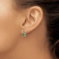 A woman wearing a silver pendant earring with a green cushion-cut stone surrounded by smaller diamonds, shown from the side view near her ear.