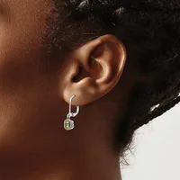 A person wearing a silver hoop earring with a small square pendant featuring a green stone and diamond accents.