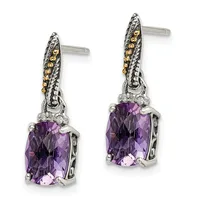 A pair of silver drop earrings with purple cushion-cut gemstones, decorated with gold and diamond accents on the posts.