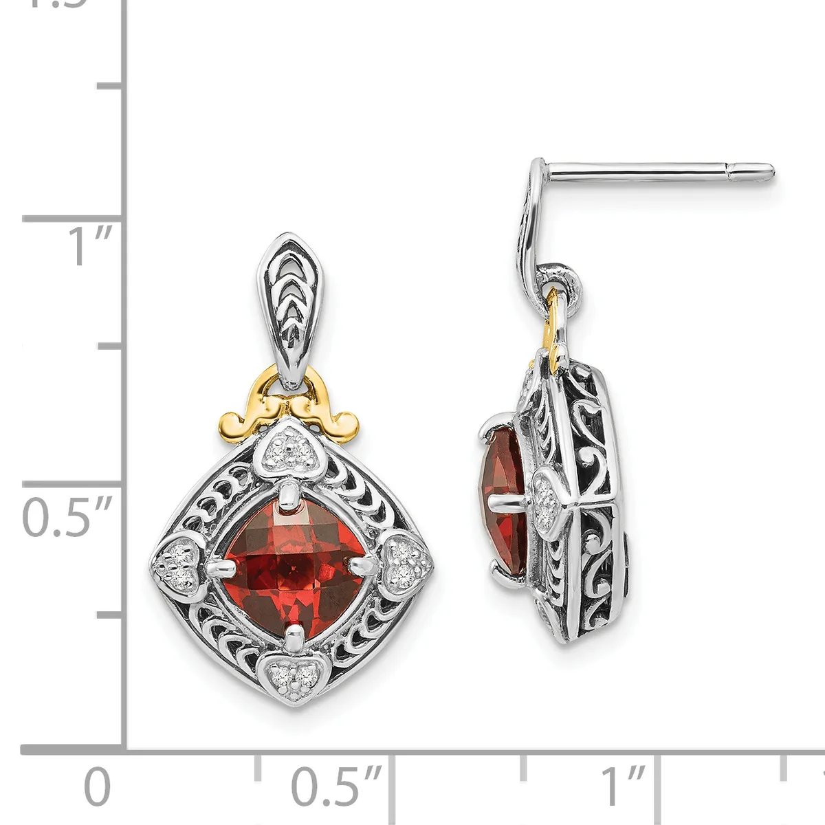 A pair of ornate silver and gold dangle earrings featuring square-cut red gemstones surrounded by scrollwork filigree and diamond accents, displayed against a measurement scale.