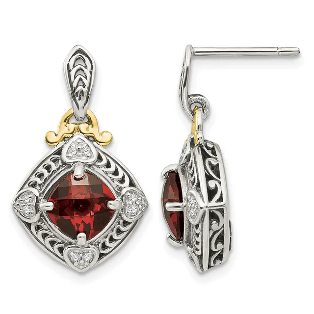 A pair of ornate silver and gold drop earrings featuring cushion-cut red gemstones surrounded by decorative filigree patterns and small diamond accents, shown from front and side views.