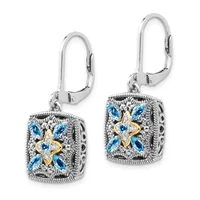 A pair of silver lever-back earrings with square ornamental pendants featuring blue topaz stones arranged in a four-pointed star pattern with gold-tone accents and textured silver borders.