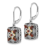 A pair of square silver lever-back earrings with ornate filigree borders, each featuring a four-pointed flower design with red gemstones and a gold-toned center.