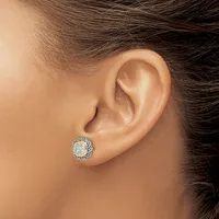 A close-up view of a person's ear wearing a round stud earring with a center diamond surrounded by a halo of smaller stones in white metal.
