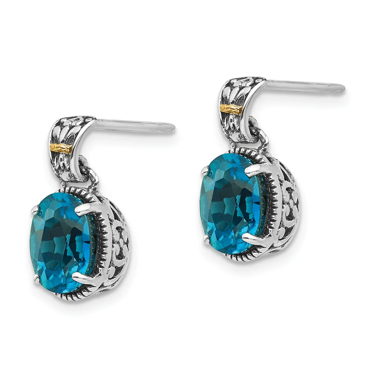 A pair of silver drop earrings with ornate filigree details and gold accents, each featuring a faceted blue topaz stone in an oval cut.