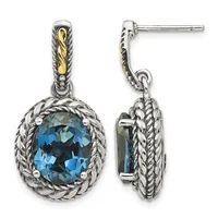 Pair of sterling silver drop earrings with twisted rope bezels framing oval blue topaz stones and gold-tone twisted bail details, shown from front and side views.