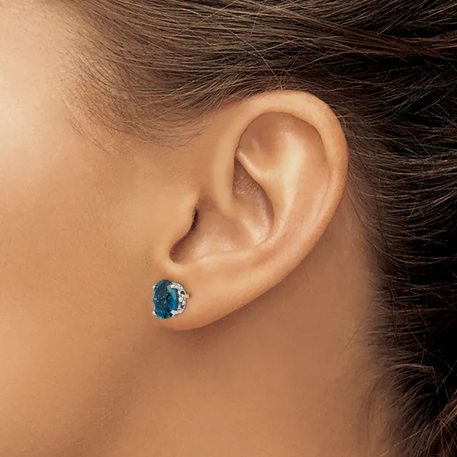 A person wearing a blue oval gemstone stud earring in their pierced earlobe, shown in profile view.