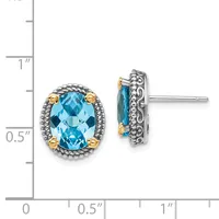 Pair of silver and gold stud earrings with oval blue topaz stones surrounded by decorative beaded and scrollwork settings, shown front and back views with measurement scale.