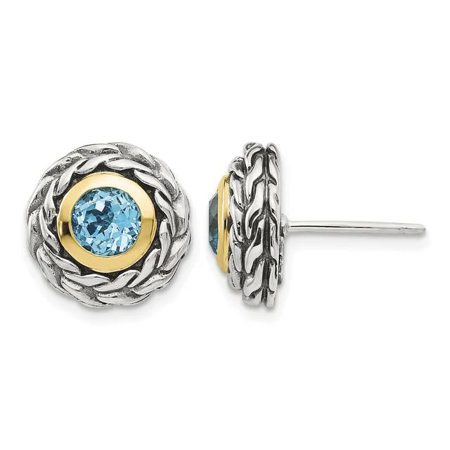 Pair of round stud earrings featuring blue topaz stones set in gold bezels, surrounded by twisted silver bezels with braided detailing, shown from front and side views.