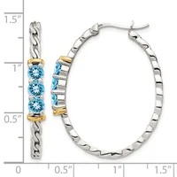 A pair of silver hoop earrings with three blue topaz stones and gold-tone accents, displayed next to a measurement scale showing approximately 1.5 inches in length.