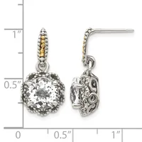 A pair of two-tone dangle earrings with cushion-cut clear stones surrounded by ornate metalwork and textured posts, shown against a measurement scale.