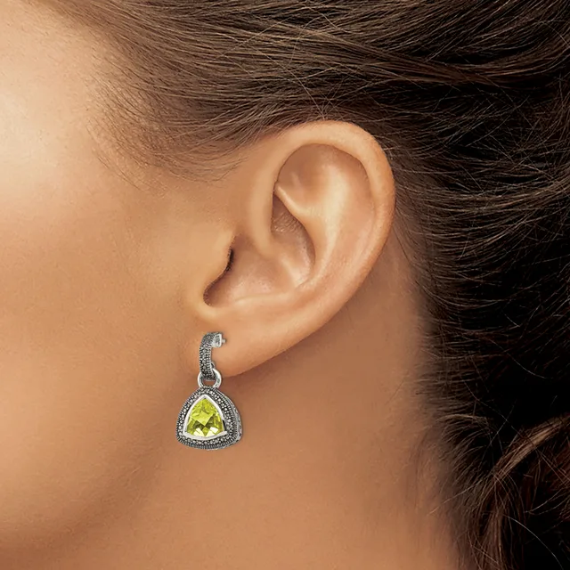 A woman wearing a triangular yellow citrine stone pendant earring with a beaded silver frame, shown from the side view of her ear.