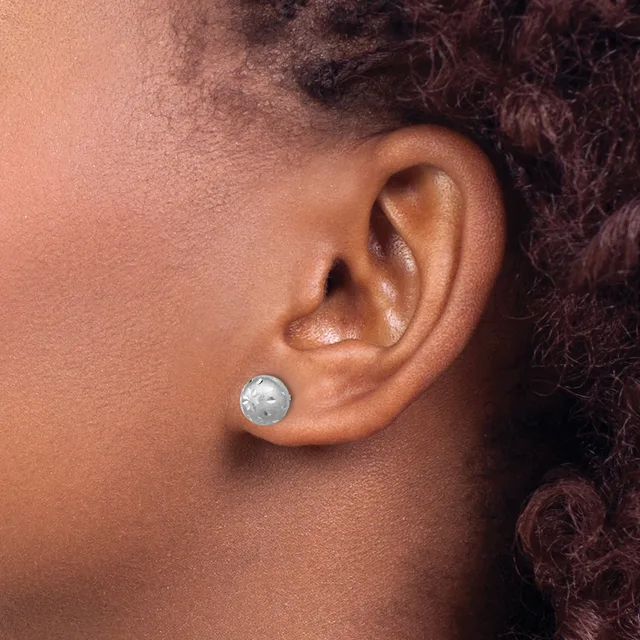 A person wearing a small round silver stud earring with a textured surface in their earlobe, shown in profile against their neck and shoulder.