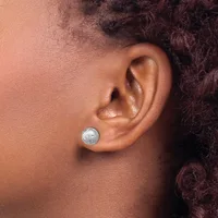 A person wearing a small round silver stud earring with a textured surface in their earlobe, shown in profile against their neck and shoulder.