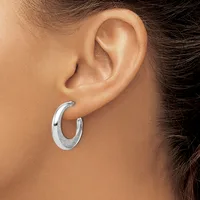 A person wearing a curved silver hoop earring in their earlobe, shown in profile against their neck and shoulder.