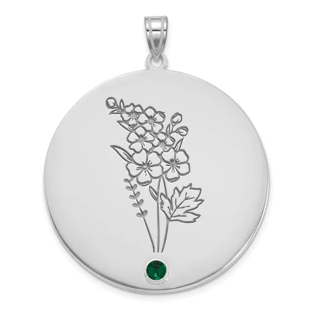 Silver circular pendant with an engraved flower bouquet design and a small emerald green stone at the bottom, suspended from a silver bail.