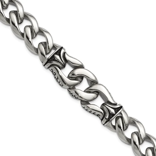 A silver curb chain bracelet with decorative ornamental links featuring scrollwork details and small stamped hallmarks, displayed diagonally against a white background.