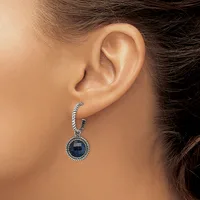 A woman wearing a silver-toned drop earring with a twisted rope-textured top loop and a round dark blue stone pendant with a beaded border, shown from the side profile.